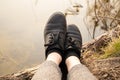 Female legs in black leather shoes on the background of the river in spring on vacation in the forest, outdoor