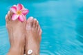 Female legs blue pool water frangipani flower Royalty Free Stock Photo