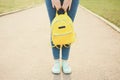 Female legs with bright fashionable yellow backpack