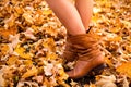 Female legs in brown boots. Yellow foliage underfoot. Autumn concept Royalty Free Stock Photo