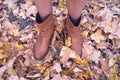 Female legs in brown boots. Yellow foliage underfoot. Autumn concept Royalty Free Stock Photo