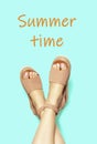 Female legs in brown sandals upside down and the inscription Summer time on blue background.