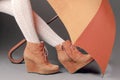 Female legs in brown suede boots under an umbrella on a gray background. Waterproof treatment for suede boots concept Royalty Free Stock Photo