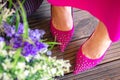 Female legs close-up. Pink shoes and dress on the summer terrace. Girl walks in the city outdoors.