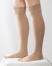 Female legs in compression stockings for varicose veins on the legs. White background. Circulation in the legs