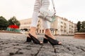 Female legs in elegant black summer shoes in fashion white jeans with a leather vintage bag on the street. Close-up Royalty Free Stock Photo