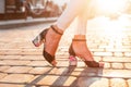 Female legs in fashion summer high heel shoes in white jeans on the background of a bright sunset. close-up Royalty Free Stock Photo