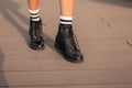 Female legs in fashionable leather black boots in stylish white striped socks. Trendy youth casual outfit. Details Royalty Free Stock Photo