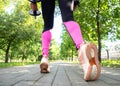 Female legs and feet in leggings and sneakers. Faceless woman does step forward with dumbbells in public park outdoor in