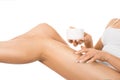 Female legs and hands with a jar of cream. Woman applying moisturizer on her perfect legs, isolated on white background. Royalty Free Stock Photo