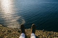 Female legs in leather boots are on the edge of a cliff