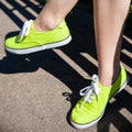 Female legs in light green sneakers.
