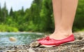 Female legs in red shoes on a background of landscape