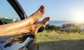 Female legs out of a car window on a background of a sea landscape. Royalty Free Stock Photo