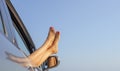 Female legs out of a car window on a background of a sea landscape. Royalty Free Stock Photo