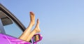 Female legs out of a car window on a background of sky. Royalty Free Stock Photo