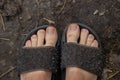 Female legs in black rubber flip flops stand on the ground top to bottom view Royalty Free Stock Photo