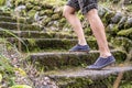 Female legs in sneakers, going up the old stone steps, against the background of a cobblestone wall. Concept of an Royalty Free Stock Photo
