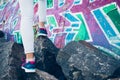 Female legs in sneakers and jeans climb over the rocks on the ba Royalty Free Stock Photo