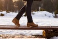Female legs are standing on bench in winter sunny day. Blurred background of snow and sunset rays. Girk is walking in park. Royalty Free Stock Photo