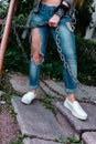 Female legs in torn jeans, close-up, girl holding a rusty chain. Royalty Free Stock Photo