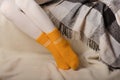 Female legs in warm white knitted tights and yellow socks on a white background made of faux fur