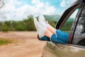 Female legs in white sneakers sticking out of the car window, close-up. The concept of car travel Royalty Free Stock Photo