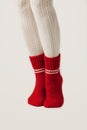 Female legs in white stockings and red knit socks.