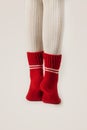 Female legs in white stockings and red knit socks.