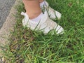 Female legs in whote leather sneakers standing on a grass in park, walking concept Royalty Free Stock Photo