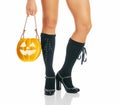 Female legs of witch and Halloween jack-o-lantern pumpkin.