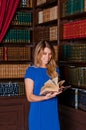 Female librarian works in the library organizing book on bookshelf