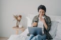 Woman life coach in headset conducts online consultation by video call on laptop in bedroom at home Royalty Free Stock Photo