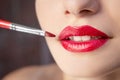 Female lips with red lipstick close-up. Makeup artist applying lipstick with a brush Royalty Free Stock Photo