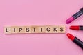 Female lipsticks on pink background. Wooden cubes with written word lipsticks. Royalty Free Stock Photo