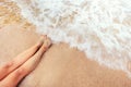 Female long feet meeting the sea wave. Summer vacations concept with sandy golden beach and foamy waves