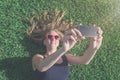 Female lying on grass and taking selfie with her smart phone Royalty Free Stock Photo