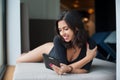 Female lying on mattress near big window, smiling and looking at tablet computer at lounge zone in the spa resort Royalty Free Stock Photo