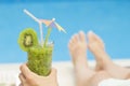 Female lying on sunbed and holding a glass of fresh kiwi smoothie Royalty Free Stock Photo