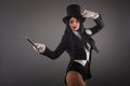 Female magician in costume suit with magic stick doing trick
