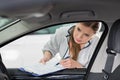 Female maintenance engineer with clipboard examining car's interior in workshop