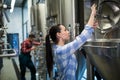 Female maintenance worker examining brewery machine
