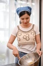 Female makes a homemade cupcake in her home kitchen, whisking her softened butter