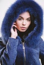 Female with makeup wear dark blue soft fur coat. Woman wear hood with fur. Fashion concept. Girl elegant lady wear