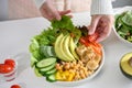 A female making a plate of Buddha bowl or plant based salad vegetables mixed