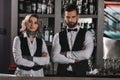 female and male bartenders standing with crossed arms