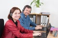 Female and male customer service agent wearing headset with colleagues working in background at office Royalty Free Stock Photo