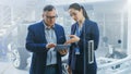 Female and Male Engineer Work in a High Tech Development Facility Holding a Tablet Computer. They Royalty Free Stock Photo