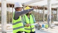 Female and male engineers survey inspection schedules for new construction projects at construction sites