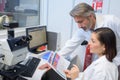 Female and male eye doctor sitting with ophthalmologic device